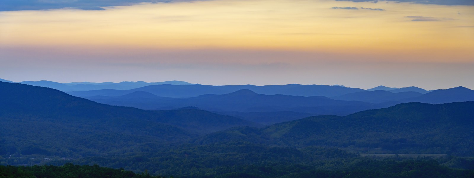 Layered mountain ridgelines at dusk under a fading sky